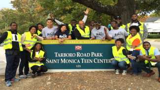 A group of park volunteers posing in front of the Tarboro Road Park sign 