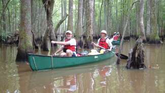 Two active adults canoeing down a river together 