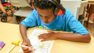 A young boy coloring a butterfly during SRIS Camp Friendly 