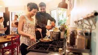 couple cooking with friends at kitchen table