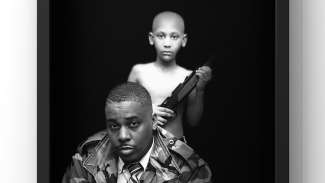 Photo on canvas by JP Jermaine Powell, a small boy stands behind the artist holding a gun