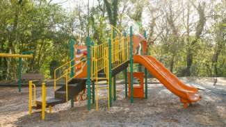 Playground structure with slide and climbing stairs ladder in bright orange, yellow and green