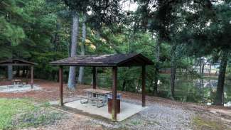 View of outdoor covered shelters with picnic tables by pond
