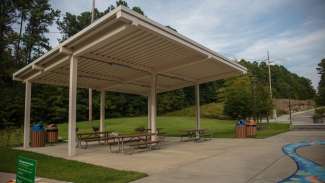 A medium size open-air picnic shelter with several picnic tables 
