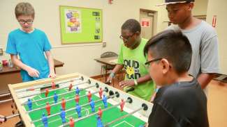 A group of young kids playing foosball together at Lions Park 