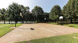 Two outdoor lighted basketball courts with a concrete surface 