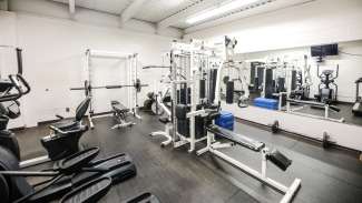 A weight room with cardio machines, free weights and other fitness equipment. 