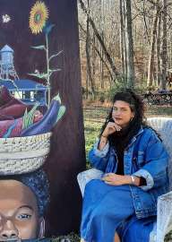 Headshot of Claire Alexandre sitting next to her artwork