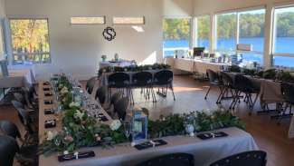 Room with tables set up for wedding with large windows showing beautiful lake