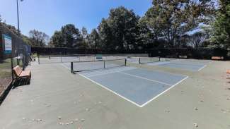 A set of six pickleball courts with nets and backboards 