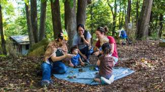 Kids and instructors on blanket in woods doing nature program