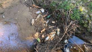Bottles, paper, and other trash in a stream at Apollo Heights Park