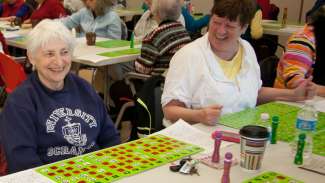 Two Active Adult participants sitting at table smiling playing bingo