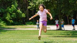 Girl jumping in grass smiling