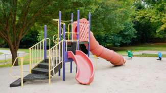 Playground equipment with climbing steps and slides with sand diggers in background
