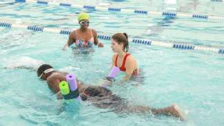 Adult swimming lesson with instructor and two swimmers in pool