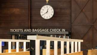 A large clock hangs above the desk that reads Tickets and Baggage Check In
