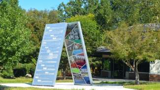 Standing outdoor exhibit of two panels leaning against each other surrounded by green trees