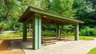 Picnic shelter with four picnic tables and trees in background