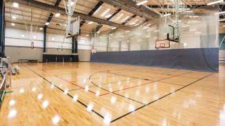 Gymnasium with two basketball courts separated by mechanical curtain