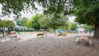 View of picnic tables with playground in background at LeVelle Moton Park