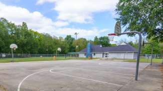 Basketball court with four hoops and trees and community center in background