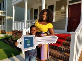 Homeowner in East College Park holds cut-out key in front of her home.