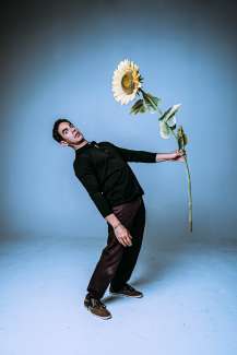 Magician Joshua Lozoff holds large sunflower in photo. 