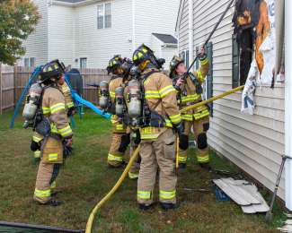 Firefighters inspect damage on side of home