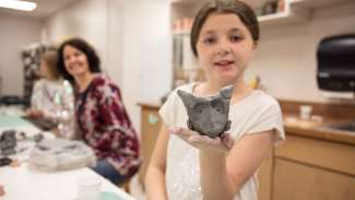 a teen shows her handbuilt pottery owl to the camera