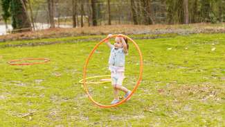 young girl playing with hula hoop in the grass