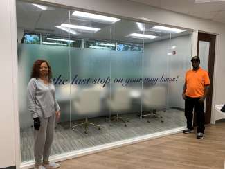 the homeowners standing beside a sign in an office building that says "the last stop on your way home"