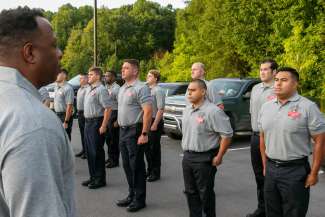 Fire academy recruits standing in formation listening to instructor
