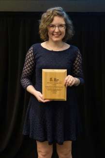Andrea Luke, executive director of CVNC,org smiles and holds a wooden award plaque