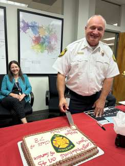 Chief Poole cuts a cake that congratulations him on 45 years of service.