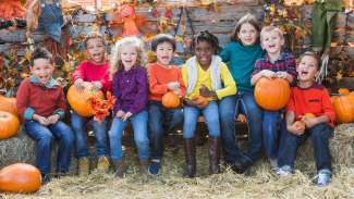 happy children smiling at a fall festival with pumpkins