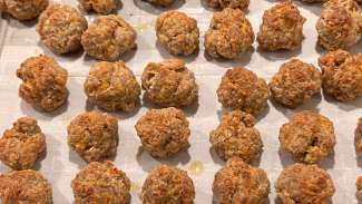 Small round sausage balls sitting on a cookie sheet after being baked