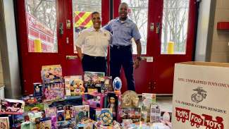 Two firefighters standing with a collection of toys for the Toys for Tots drive.