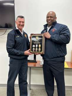 Fire Chief Griffin hands Chief Toms a retirement plaque