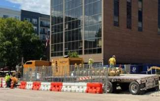 Images shows large construction drill being loaded onto truck. 