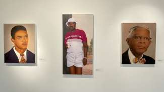 Three paintings of Black men on canvas in a gallery. 