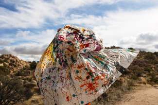 photograph of a large swath of white fabric splashed with paint. 