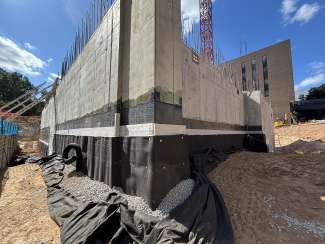 image shows the basement walls of the City Hall in construction with the waterproofing and storm drain pipes. 