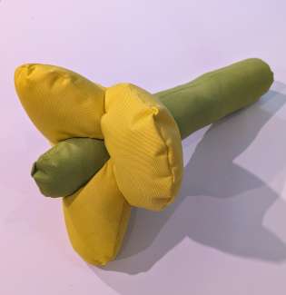 Bright yellow and green stuffed fabric flower, part of a sculpture. 