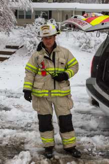 Chief Keith Wilder dressed in fire gear standing in a yard with snow on the ground.