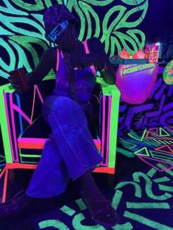 Photo of a person sitting in a neon chair at the Find Your Glimmer exhibition