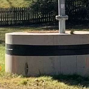 Large round cement block with pipe sticking out the top
