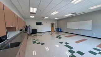 A medium size classroom with tables, chairs, a white board and two sinks at Marsh Creek 
