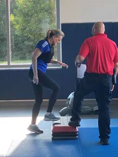 Mayor doing a step-up exercise in a gym with an RPD trainer standing next to her