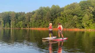 two adults on paddle boards on a lake